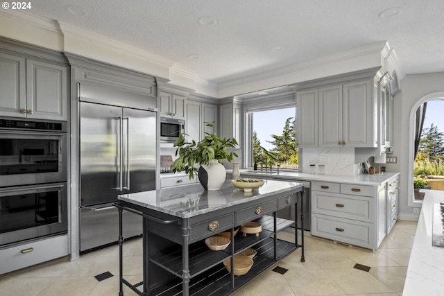 kitchen with a healthy amount of sunlight, gray cabinetry, and built in appliances