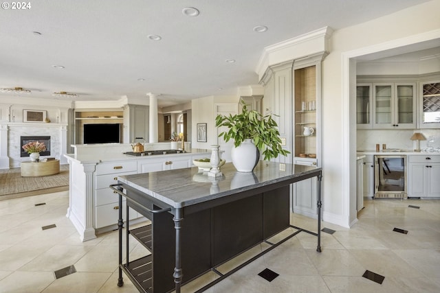 kitchen with a kitchen breakfast bar, wine cooler, a high end fireplace, a center island, and decorative columns