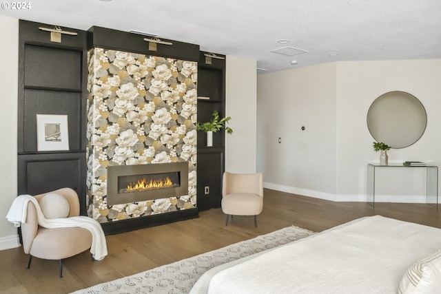 bedroom featuring wood-type flooring, a textured ceiling, and a fireplace