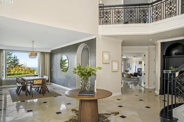 foyer entrance featuring light tile patterned floors, ornamental molding, a towering ceiling, and a chandelier