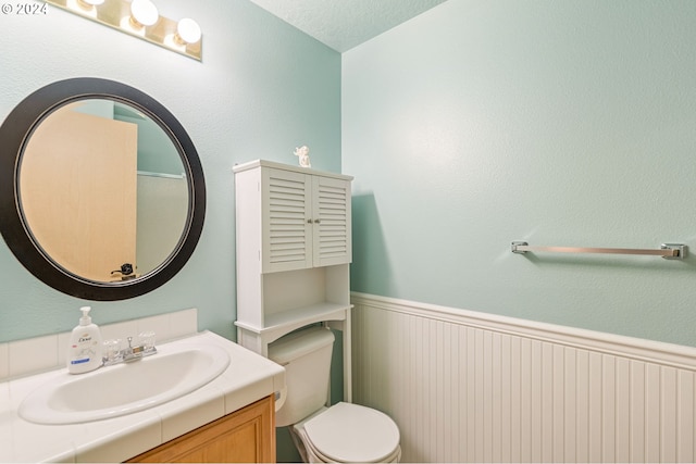 bathroom featuring vanity, a textured ceiling, and toilet