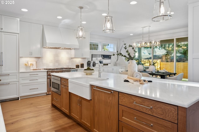 kitchen with brown cabinetry, custom range hood, and a sink