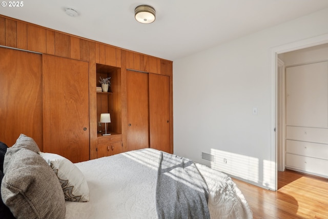 bedroom featuring multiple closets and light hardwood / wood-style flooring