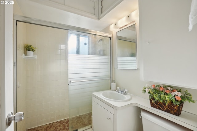 bathroom featuring vanity, toilet, and a tile shower