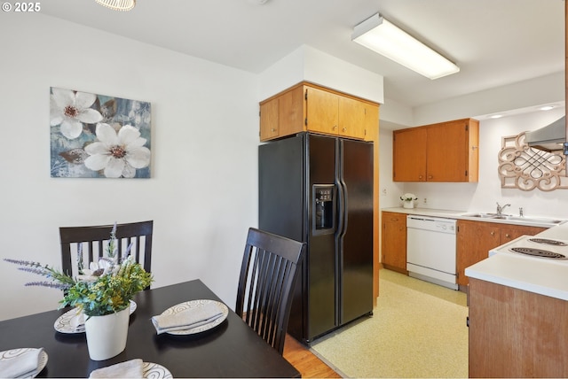 kitchen with white dishwasher, sink, and black fridge