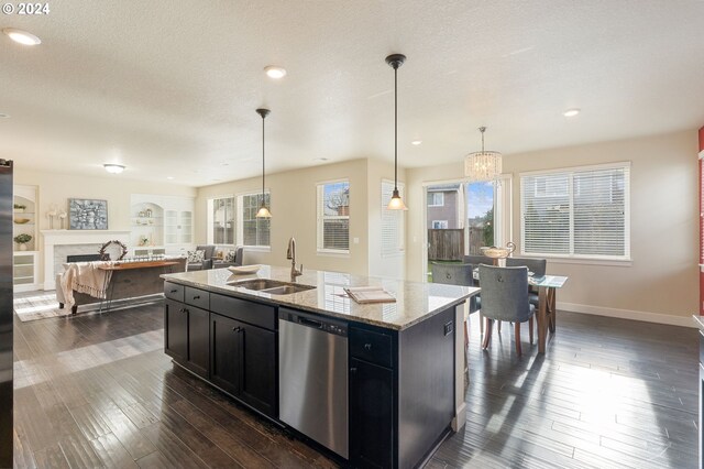 kitchen featuring a sink, dishwasher, a fireplace, dark wood-style floors, and dark cabinets