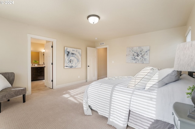 bedroom with light carpet, visible vents, ensuite bathroom, and baseboards