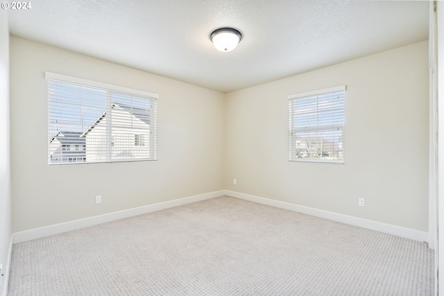 carpeted spare room with a textured ceiling and baseboards