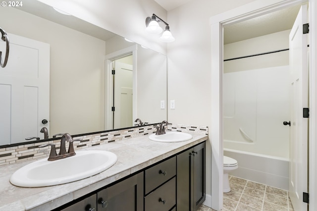 full bath featuring a sink, backsplash, double vanity, and toilet