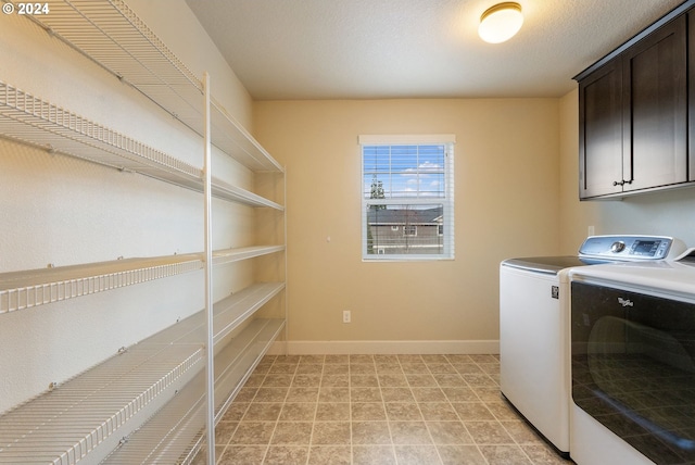 clothes washing area with baseboards, cabinet space, a textured ceiling, and washer and clothes dryer