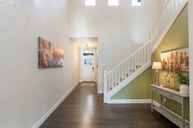 entryway with baseboards, stairs, a towering ceiling, and hardwood / wood-style flooring