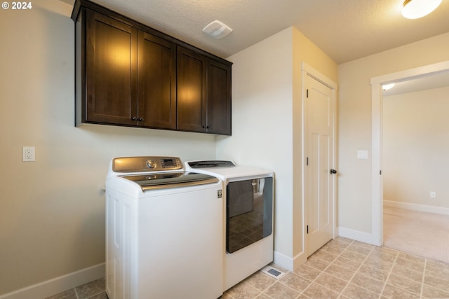 clothes washing area with visible vents, baseboards, cabinet space, a textured ceiling, and independent washer and dryer