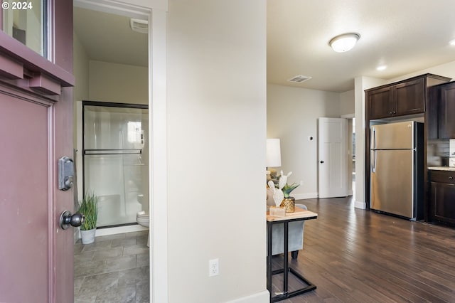 kitchen with visible vents, dark brown cabinetry, light countertops, freestanding refrigerator, and dark wood-style floors