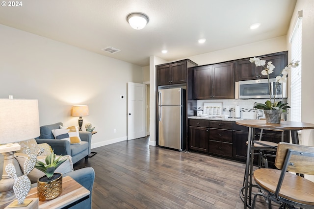 kitchen with visible vents, dark wood-type flooring, tasteful backsplash, stainless steel appliances, and dark brown cabinetry