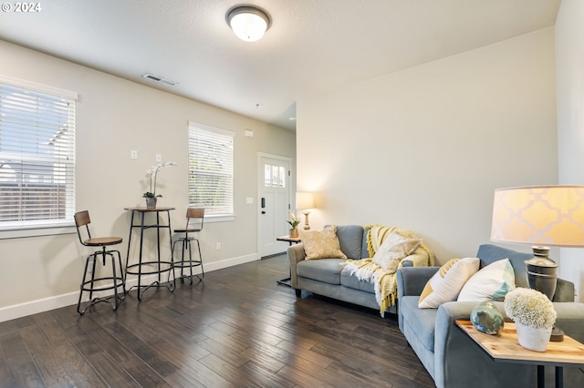 living area featuring visible vents, baseboards, and wood finished floors