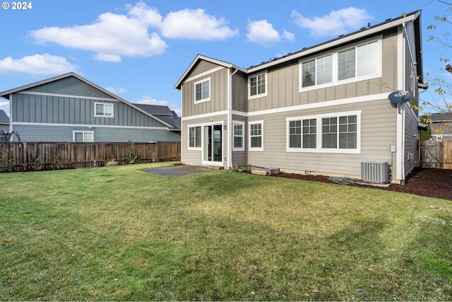 rear view of house featuring board and batten siding, cooling unit, a fenced backyard, a yard, and a patio