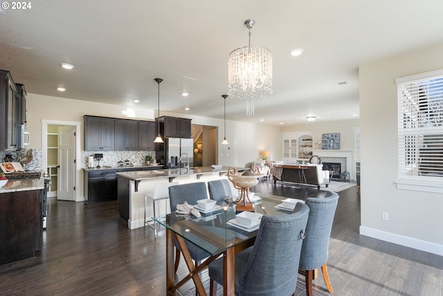 dining space featuring dark wood finished floors, recessed lighting, an inviting chandelier, a fireplace, and baseboards