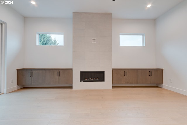 unfurnished living room featuring light wood-style flooring, recessed lighting, baseboards, and a tile fireplace