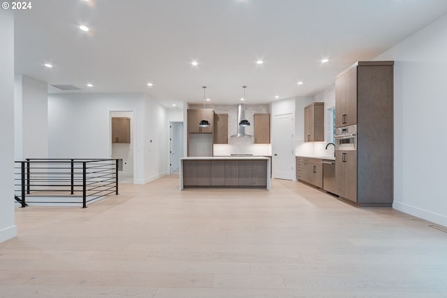 kitchen featuring light wood-style flooring, a center island, recessed lighting, appliances with stainless steel finishes, and wall chimney range hood