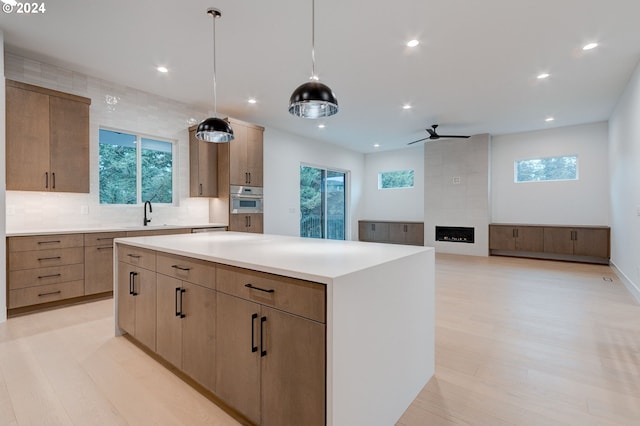 kitchen featuring light countertops, light wood-style floors, stainless steel oven, tasteful backsplash, and a center island