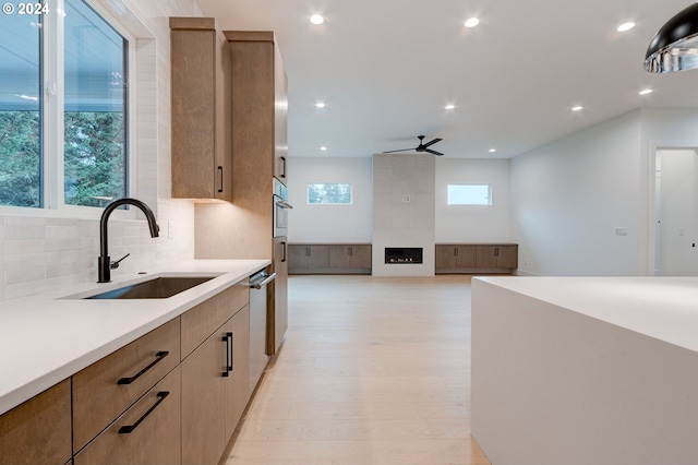 kitchen with a sink, light countertops, light wood-style floors, appliances with stainless steel finishes, and tasteful backsplash