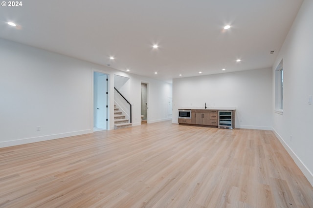 below grade area with stairway, recessed lighting, beverage cooler, and light wood finished floors