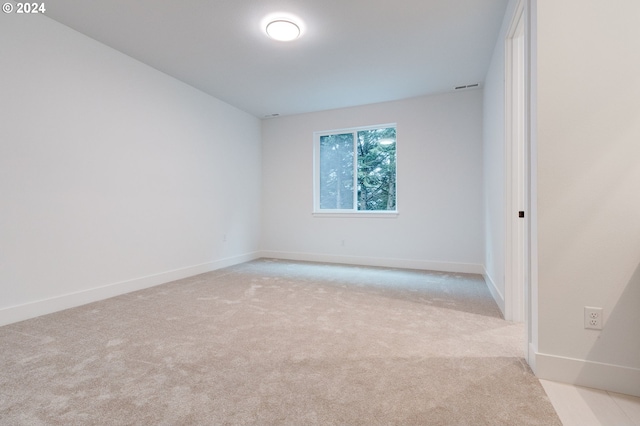 spare room featuring visible vents, light colored carpet, and baseboards