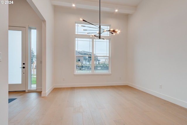 entrance foyer with beamed ceiling, baseboards, a notable chandelier, and wood finished floors