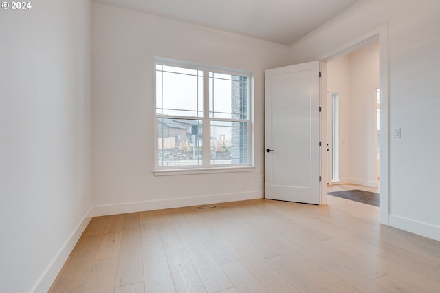 spare room with visible vents, light wood-type flooring, and baseboards