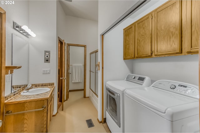 clothes washing area with cabinets, sink, and washer and dryer