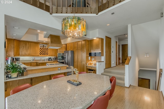 kitchen with a breakfast bar, kitchen peninsula, light wood-type flooring, appliances with stainless steel finishes, and custom range hood