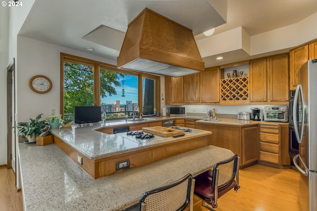 kitchen featuring kitchen peninsula, custom range hood, light wood-type flooring, and light stone counters