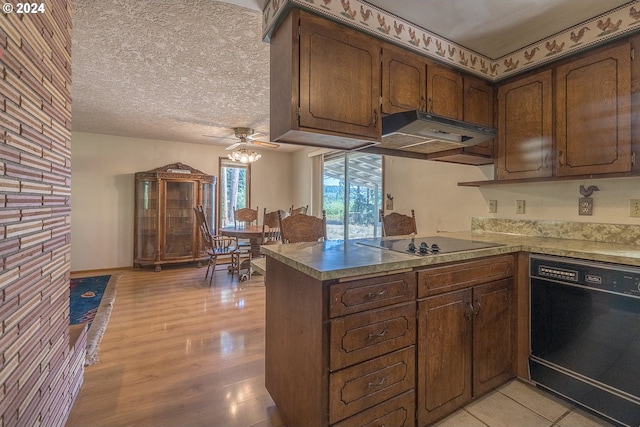 kitchen featuring light wood finished floors, black appliances, under cabinet range hood, a peninsula, and a textured ceiling