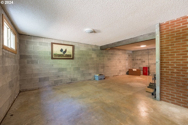 basement with a textured ceiling and concrete block wall