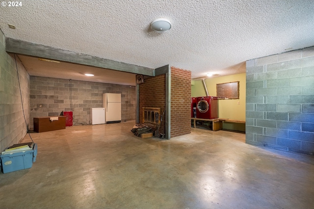 finished below grade area with concrete block wall, a fireplace, freestanding refrigerator, and a textured ceiling