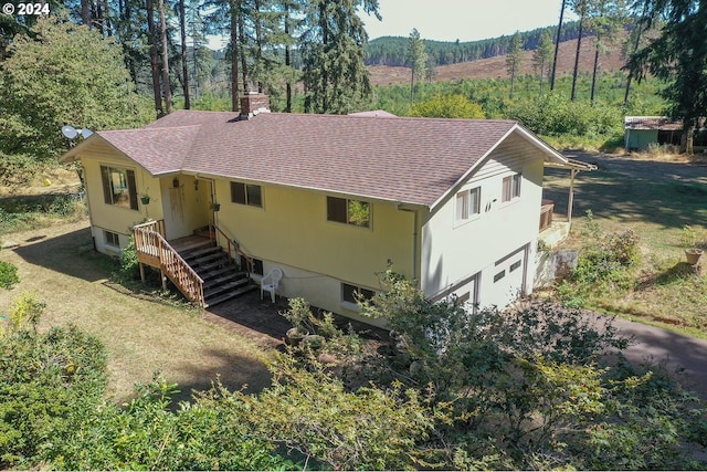 view of front of property featuring driveway, roof with shingles, a front yard, a garage, and a chimney