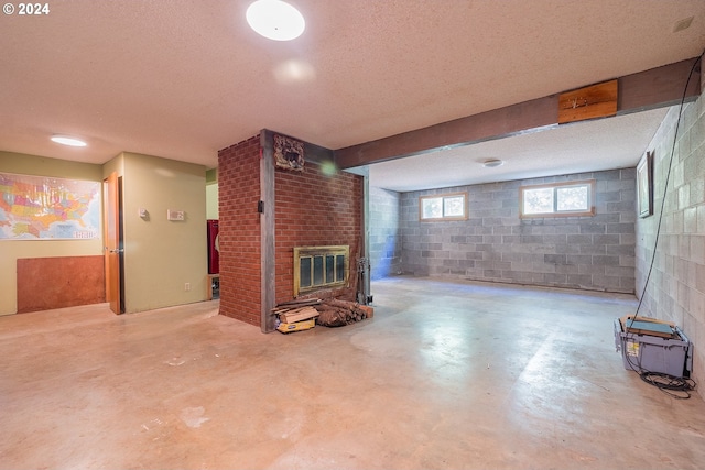 below grade area with a textured ceiling, a glass covered fireplace, and concrete block wall