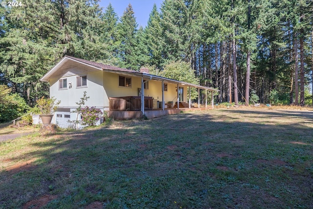 view of front of house with a front yard, a forest view, and a garage