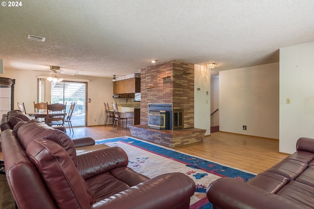 living room featuring wood finished floors, baseboards, visible vents, ceiling fan, and a textured ceiling