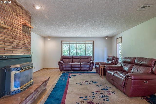 living room featuring visible vents, a textured ceiling, and wood finished floors