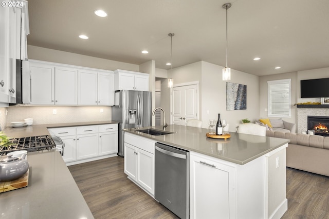 kitchen featuring dark hardwood / wood-style flooring, a kitchen island with sink, a fireplace, and stainless steel appliances