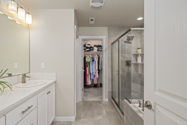 bathroom with tile patterned floors, vanity, a textured ceiling, and walk in shower