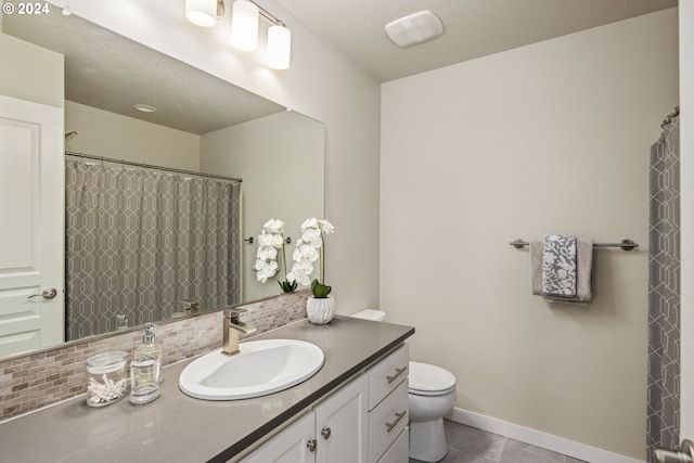 bathroom featuring tile patterned flooring, vanity, toilet, and backsplash