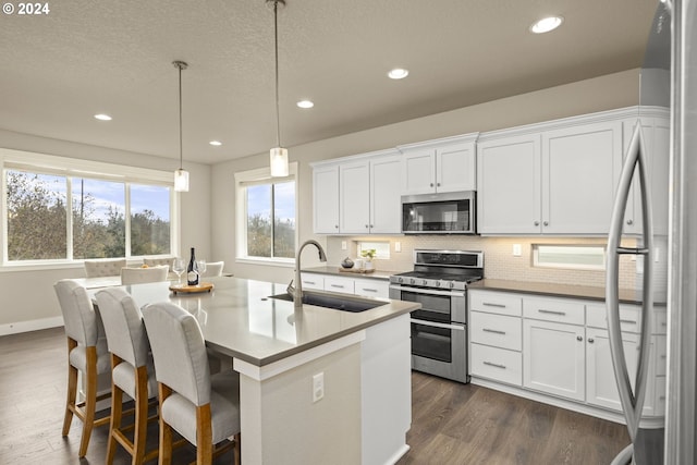 kitchen with hanging light fixtures, white cabinetry, sink, and appliances with stainless steel finishes