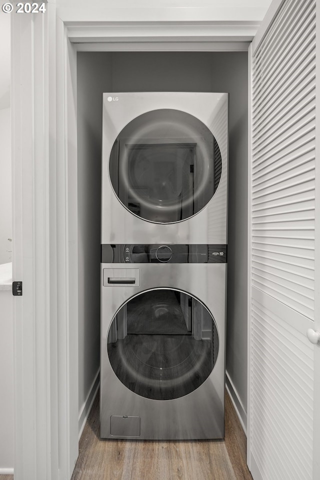 clothes washing area featuring stacked washer / dryer and hardwood / wood-style flooring