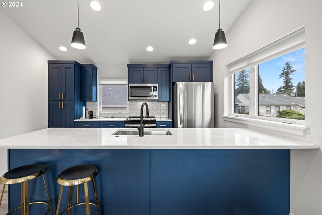 kitchen with backsplash, stainless steel appliances, blue cabinets, and hanging light fixtures