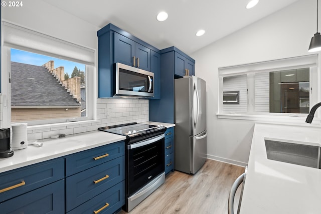 kitchen featuring appliances with stainless steel finishes, decorative light fixtures, tasteful backsplash, light wood-type flooring, and vaulted ceiling