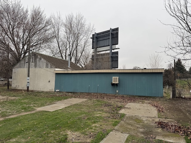 view of property exterior with a wall mounted AC and a yard