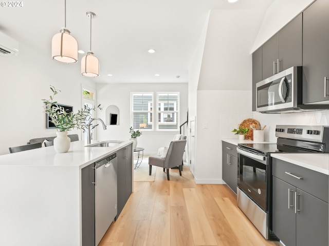 kitchen featuring modern cabinets, appliances with stainless steel finishes, hanging light fixtures, light countertops, and a sink