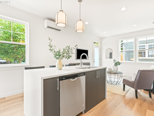 kitchen with sink, a kitchen island with sink, light hardwood / wood-style floors, dishwasher, and a wall unit AC